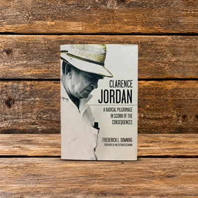 Front cover of Clarence Jordan: A Radical Pilgrimage in Scorn of the Consequences, featuring a historic photograph on the book cover, photographed on a rustic wooden surface.