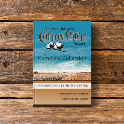 Front cover of Clarence Jordan's Cotton Patch Gospel: The Complete Collection, featuring a blue sky, cotton field, and an introduction by Jimmy Carter, displayed against a rustic wooden plank background.