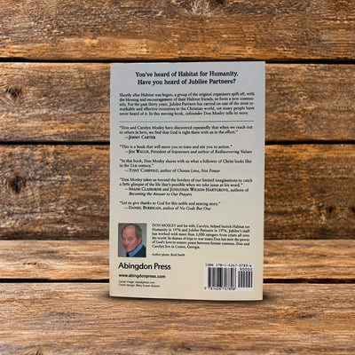 Back cover of Faith Beyond Borders by Don Mosley with Joyce Hollyday, featuring a book summary, endorsements, author biography, and barcode, photographed on a rustic wooden surface.