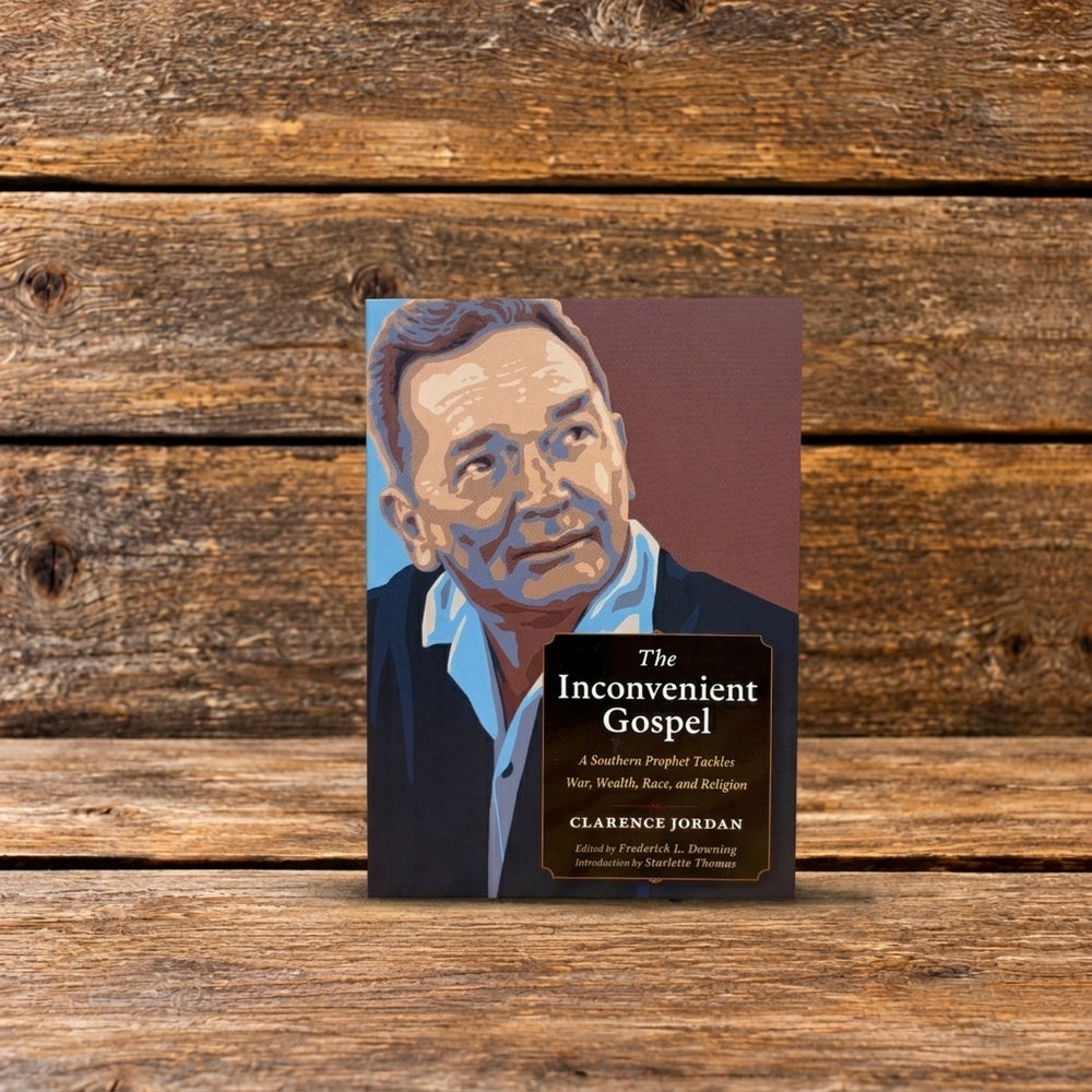 Front cover of The Inconvenient Gospel by Clarence Jordan, featuring an illustrated portrait of Jordan, photographed on a rustic wooden surface.