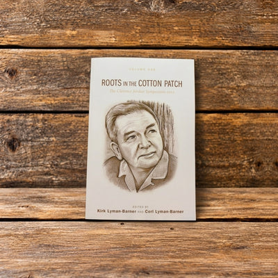 Front cover of Roots of the Cotton Patch, Volume 1, displayed against a rustic wooden background.