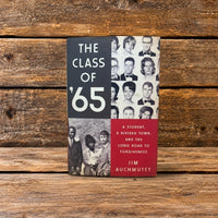 Front cover of The Class of '65, featuring a book displayed upright against a rustic wooden background.