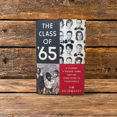 Front cover of The Class of '65, featuring a book displayed upright against a rustic wooden background.