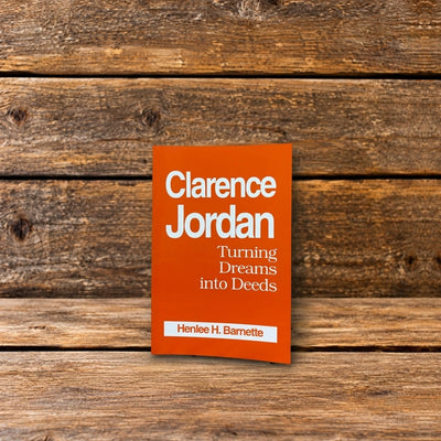 Front cover of Clarence Jordan: Turning Dreams into Deeds by Henlee H. Barnette, featuring an orange book cover, photographed on a rustic wooden surface.